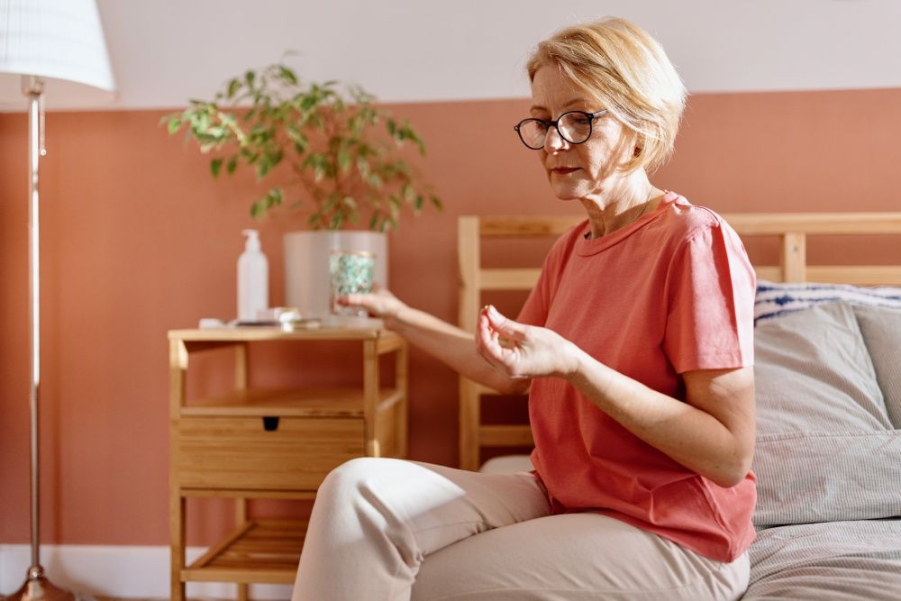 Frau sitzt auf dem Bett und nimmt eine Tablette